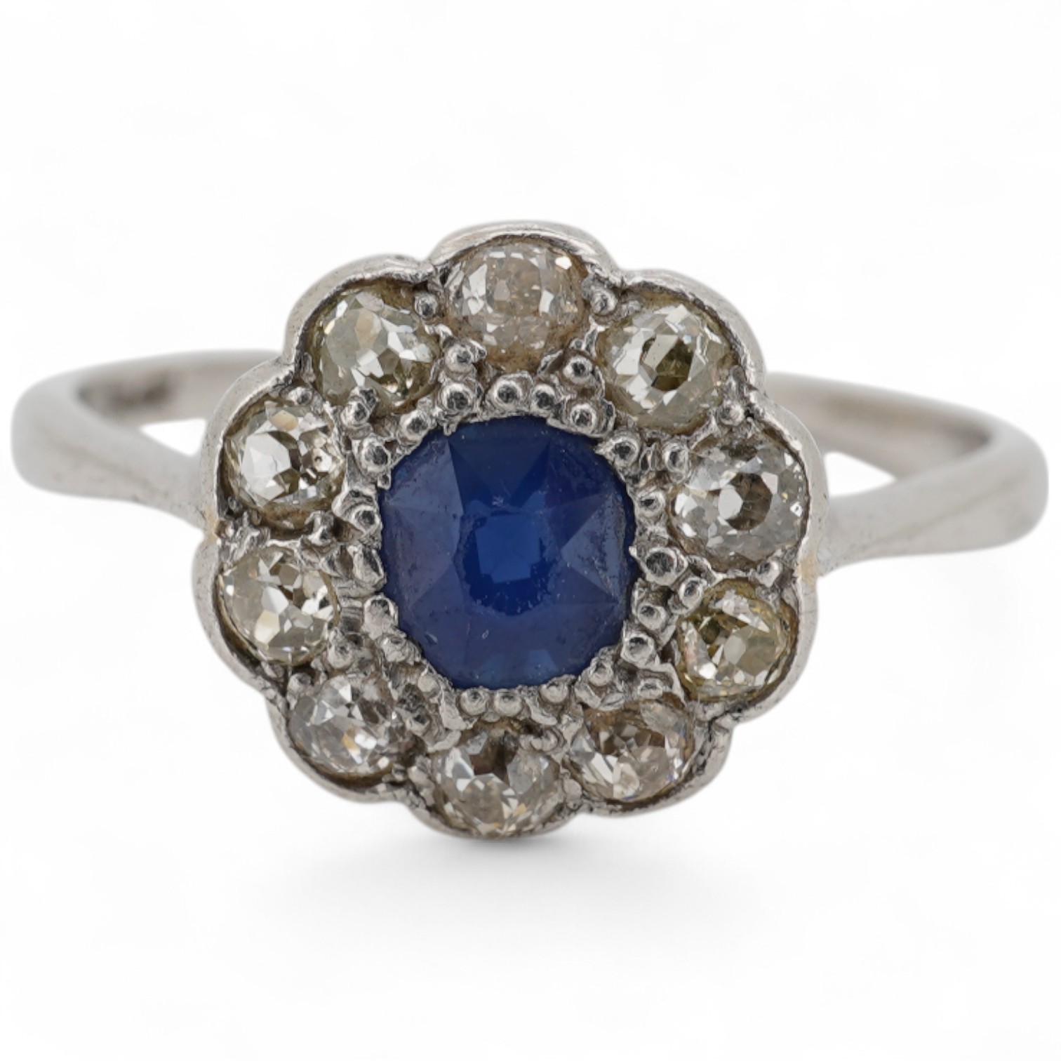 A 1920's white metal(stamped plat), sapphire and diamond set circular flower head cluster ring, size J, gross weight 2.7 grams.